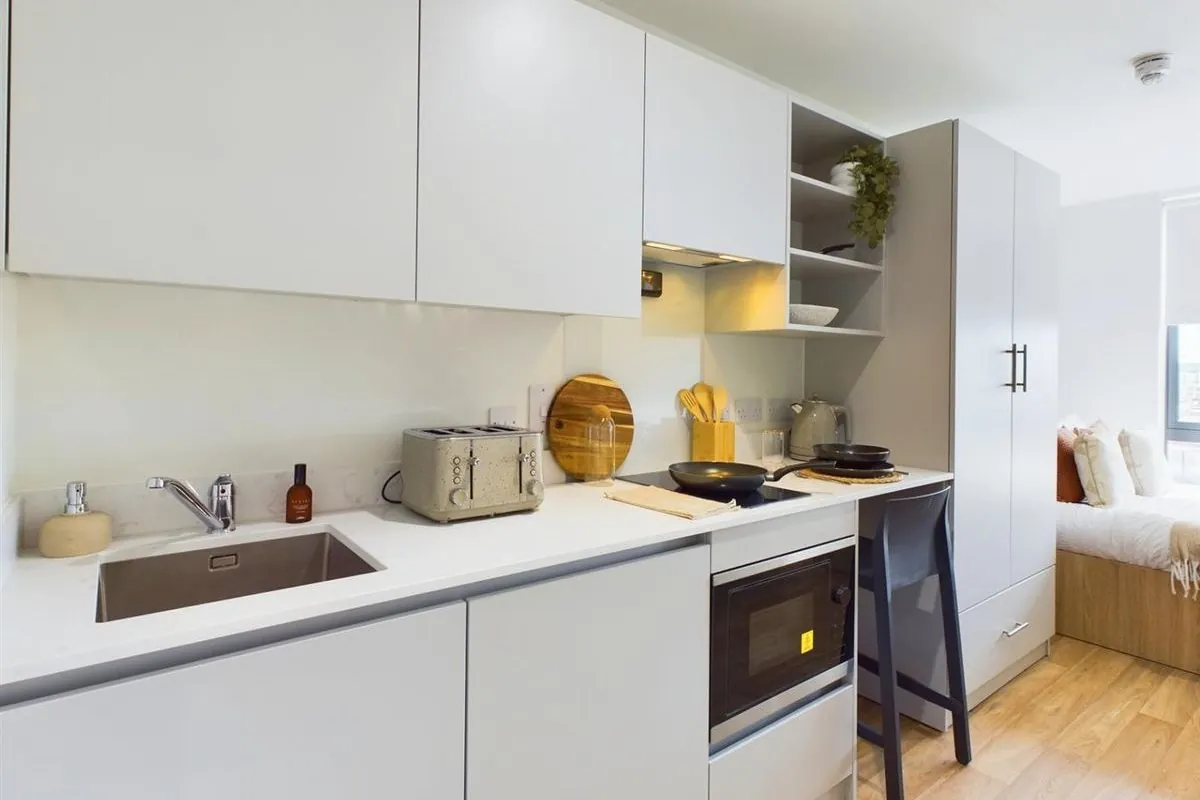 Fitted white worktop, sink and integrated appliances in a student studio
