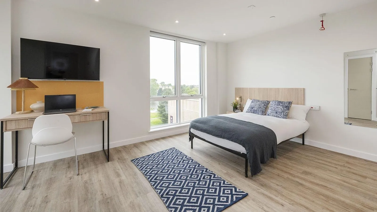 Studio at Bulk Road, Lancaster: a double bed made up, a wall-mounted TV above the desk and a full-height mirror by the window