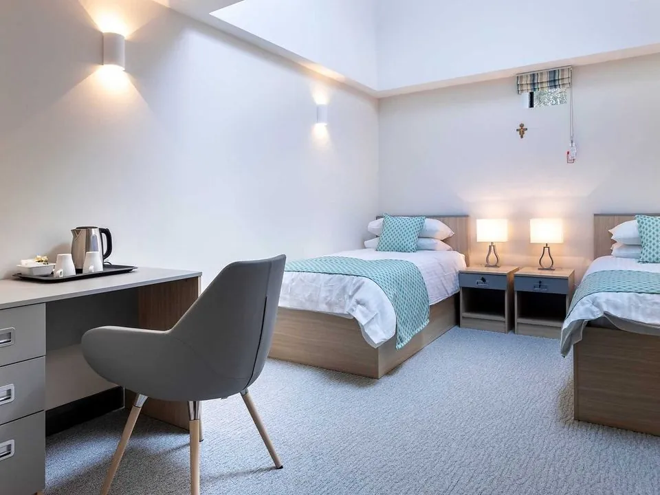 Twin bedroom with fitted bedside furniture and a writing desk